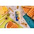 The product cinnamon, sugar & co is in the middle of the picture, with waffles, cardamom capsules and cinnamon sticks next to it.