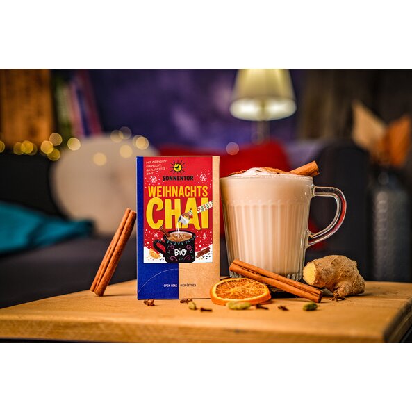 Cup of Christmas chai with milk foam, cinnamon and SONNENTOR "Christmas Chai" tea package